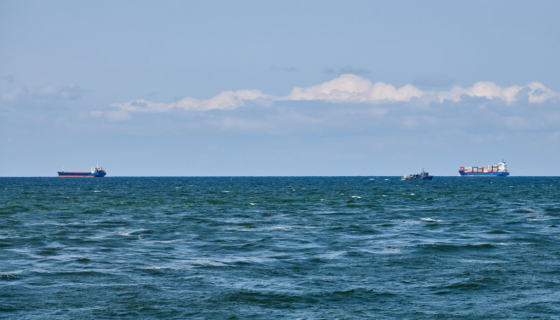 Container cargo ships in distance, import export business trade logistic and transportation, container cargo ships boats in open blue sea. Freight shipping maritime, nautical vessel