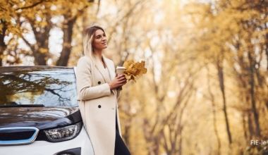 Girl have autumn trip by car. Modern brand new automobile in the forest.